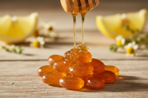 Bonbons au miel dorés avec du miel liquide qui coule d'un bâtonnet en bois sur une surface naturelle.